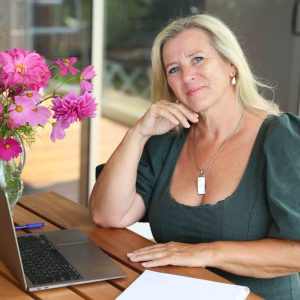 Vivian Dunstan, ADHD educator and founder of ADHD Support Australia, seated at a desk with a laptop, notebook, and pink flowers, portraying a calm and focused work environment for online advocacy and parent support