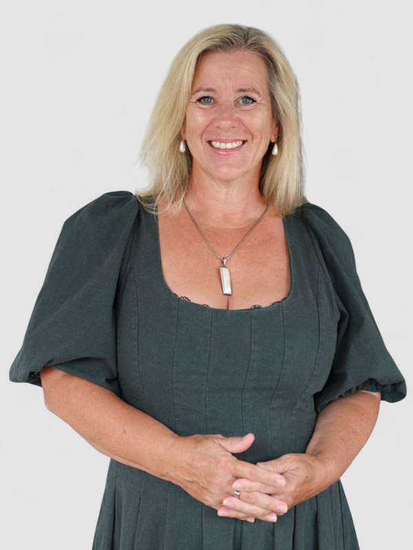 Blonde woman in green dress smiling into the camera.